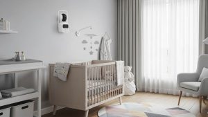 Modern nursery with pan-tilt-zoom baby monitor camera mounted on wall overlooking crib