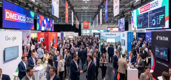 Thousands of digital marketing professionals networking on the busy exhibition floor at DMEXCO 2026 inside Koelnmesse, Cologne, with branded exhibitor stands and large digital screens in the background