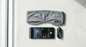 Fabric headband and silicone earbuds styles of sleep headphones on linen.